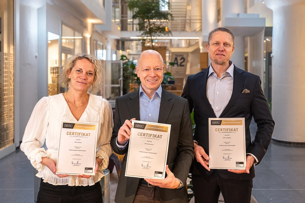 tre glada personer håller upp sina certifikat