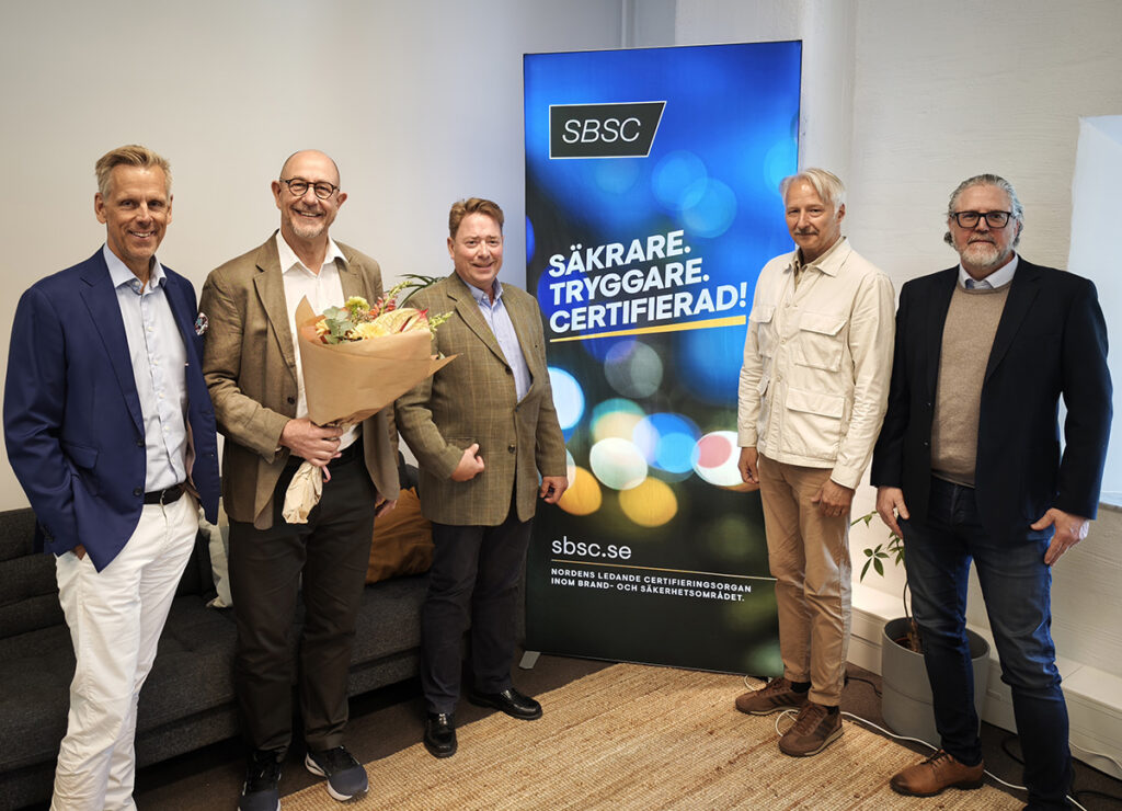 Fem representanter från SBSC står samlade vid en SBSC-rollup i samband med bolagsstämman i maj 2026. En av personerna håller i en blomsterbukett.